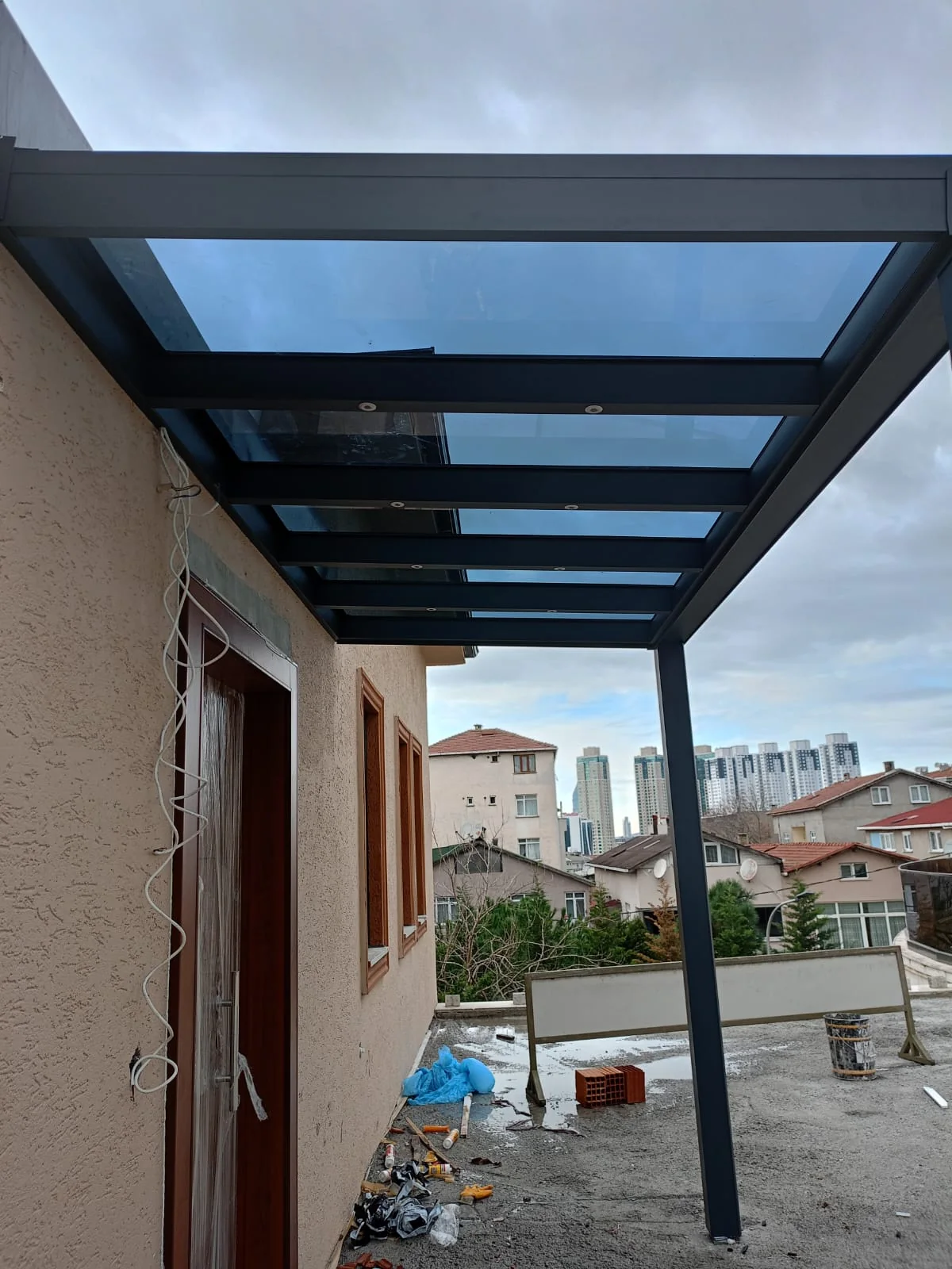Villa girişinde şeffaf cam sundurma ve rüzgârlık detayı 1