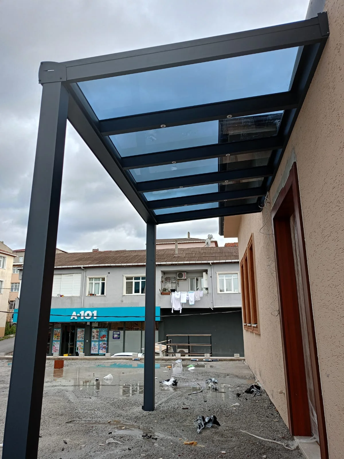 Villa girişinde şeffaf cam sundurma ve rüzgârlık detayı 2