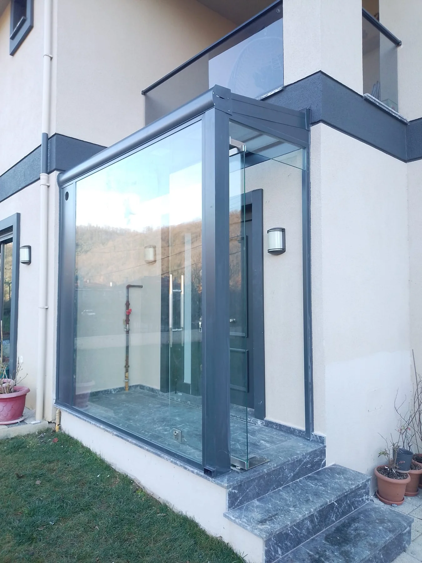 Villa girişinde şeffaf cam sundurma ve rüzgârlık detayı 3