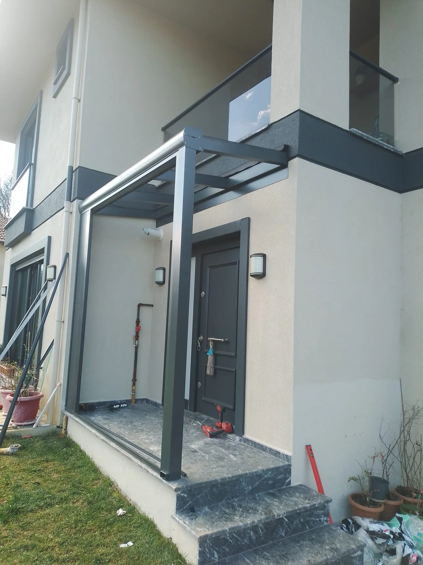 Villa girişinde şeffaf cam sundurma ve rüzgârlık detayı 4